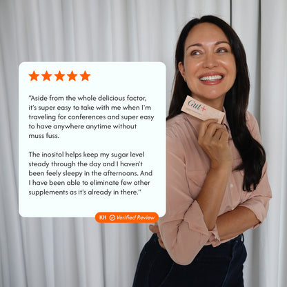 A woman smiling and holding a pink GUT+ supplement box, with a large white review card overlaid on the left showing a five-star quote and orange text. The background is a soft white curtain.