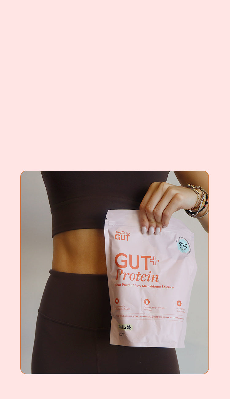 Person holding a 'GUT + Protein' package against a pink background